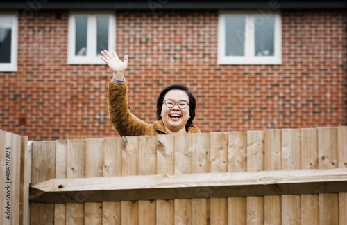 happy friendly neighbour waving over a garden fence saying hello photo