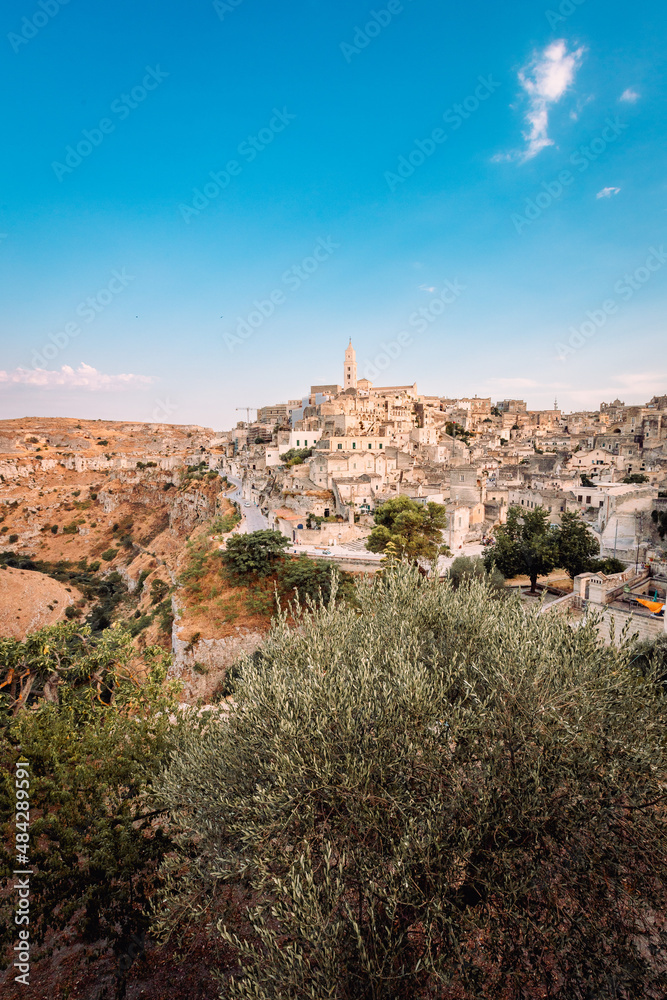 Wide view of the Sassi di Matera from the Belvedere Colombo (Church of Sant'Agostino), blue sky with clouds, vertical
