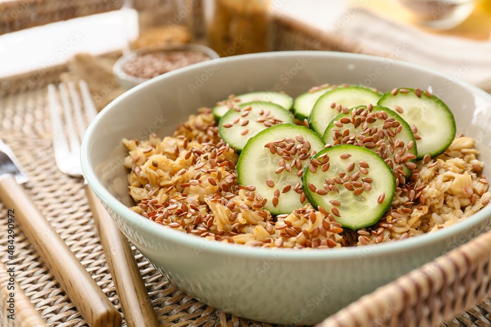 Bowl with tasty oatmeal, flax seeds and cucumber on tray, closeup Bowl with tasty oatmeal, flax seeds and cucumber on tray, closeup