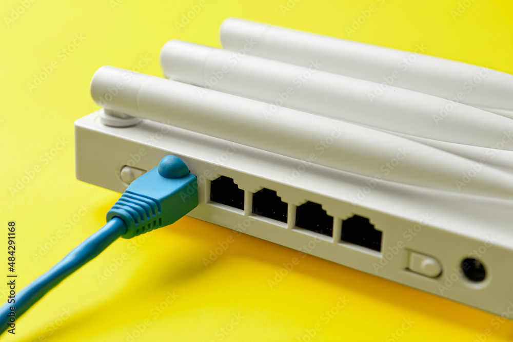 Wi-Fi router with antennas and network cable on color background Wi-Fi router with antennas and network cable on color background
