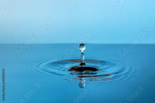 A high splash of a blue drop of water, on the surface of vibration in the form of blurring circles. Great idea for design