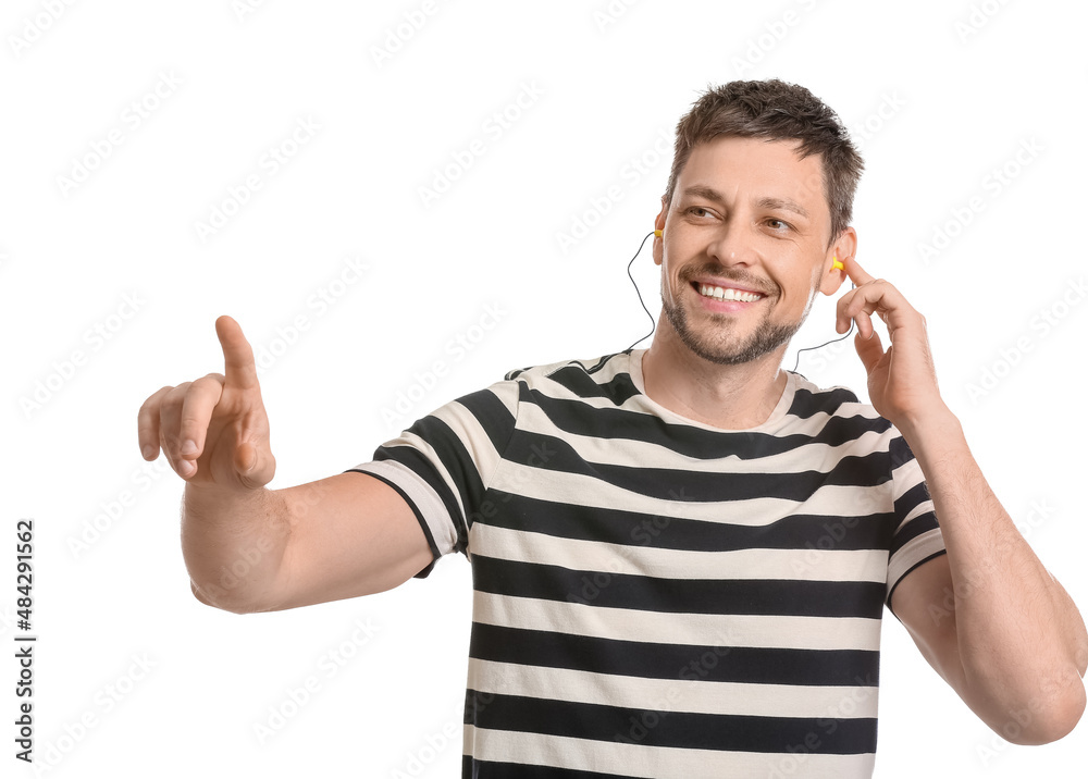 Handsome man with ear plugs pointing at something on white background Handsome man with ear plugs pointing at something on white background