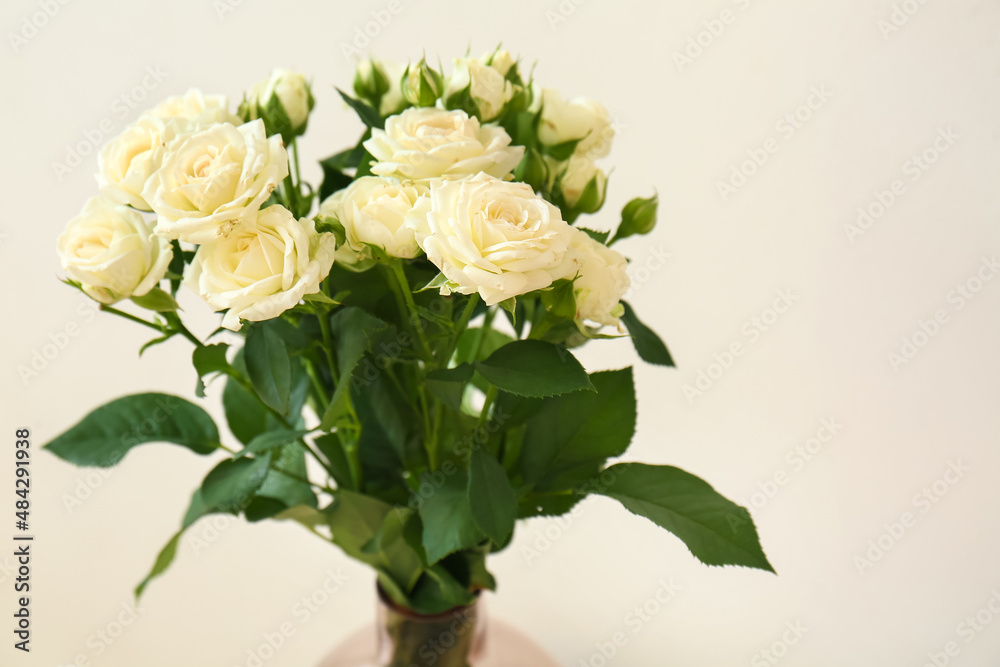Vase with bouquet of beautiful fresh roses near white wall, closeup