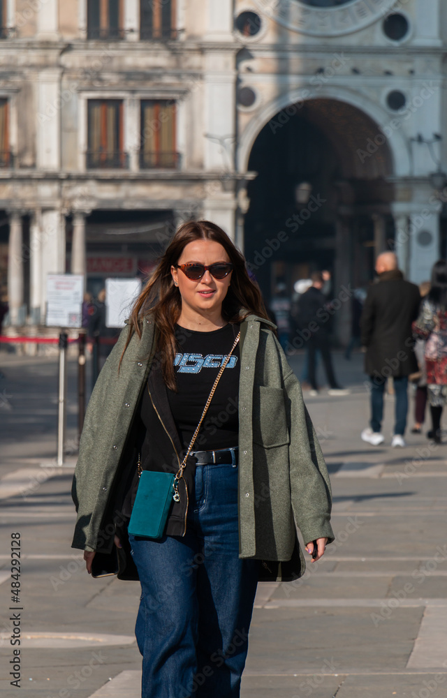 Fototapeta premium woman walking in the city, wearing sunglasses and a stylish outfit.