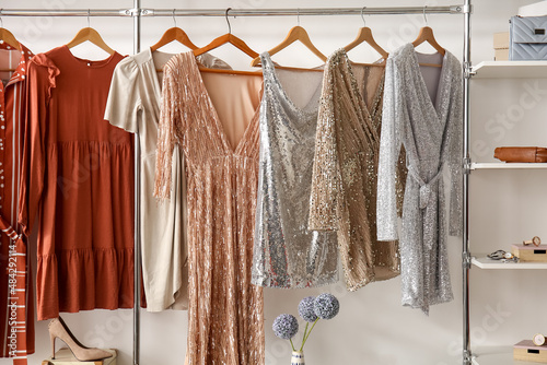 Stylish dresses hanging in wardrobe in dressing room photo