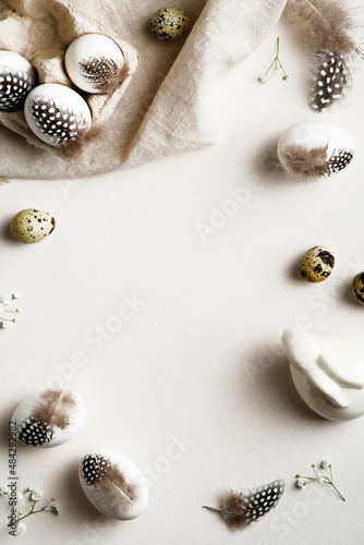 Easter vertical background. Easter frame made of Easter eggs decorated feathers with gypsophila flowers. Flat lay, top view, copy space. © photoguns