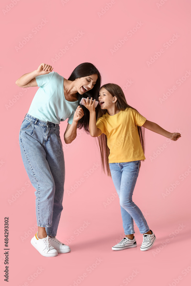 Happy dancing woman and her daughter on color background