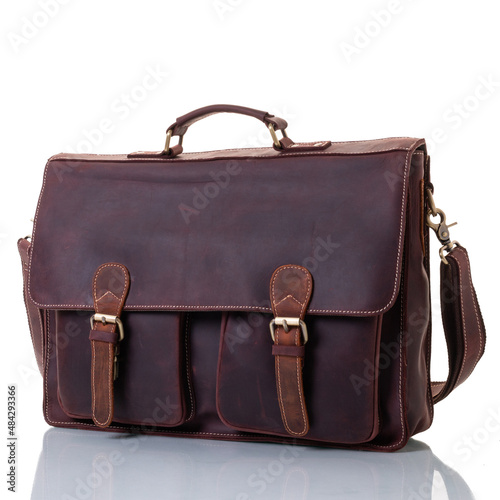 Brown leather briefcase with pockets. One handle and shoulder strap. Flap with fasteners. Brass fittings