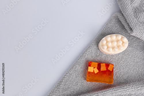 Handmade soap in white and orange on a gray terry towel. Bath accessories. Massage soap with essential oils