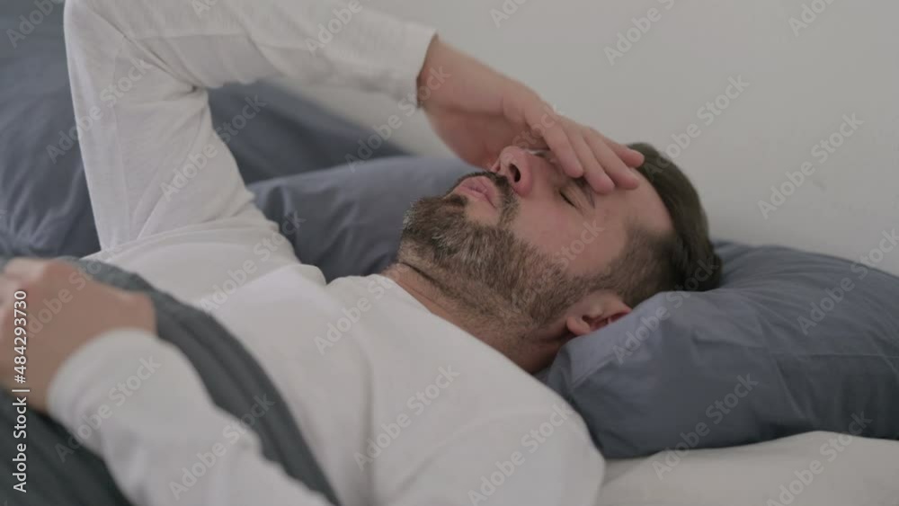 Man having Headache while Sleeping in Bed