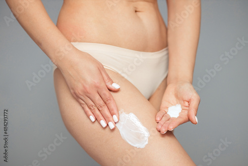 Body care. Woman applying cream on her legs. Women's use of anti-cellulite cream