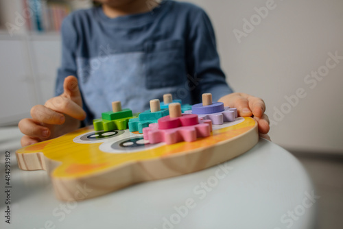 Beautiful toddler play with a wooden frame puzzle geometric figure toys at home. Toddler play with a color educational toy. Child development. Baby hands. View from above. Detail.