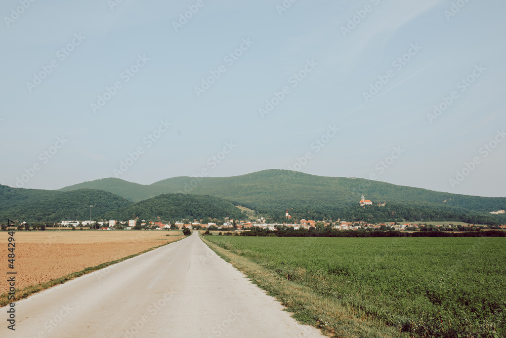 Road and fields with hills and village in the background taken on sunny summer day Road and fields with hills and village in the background taken on sunny summer day