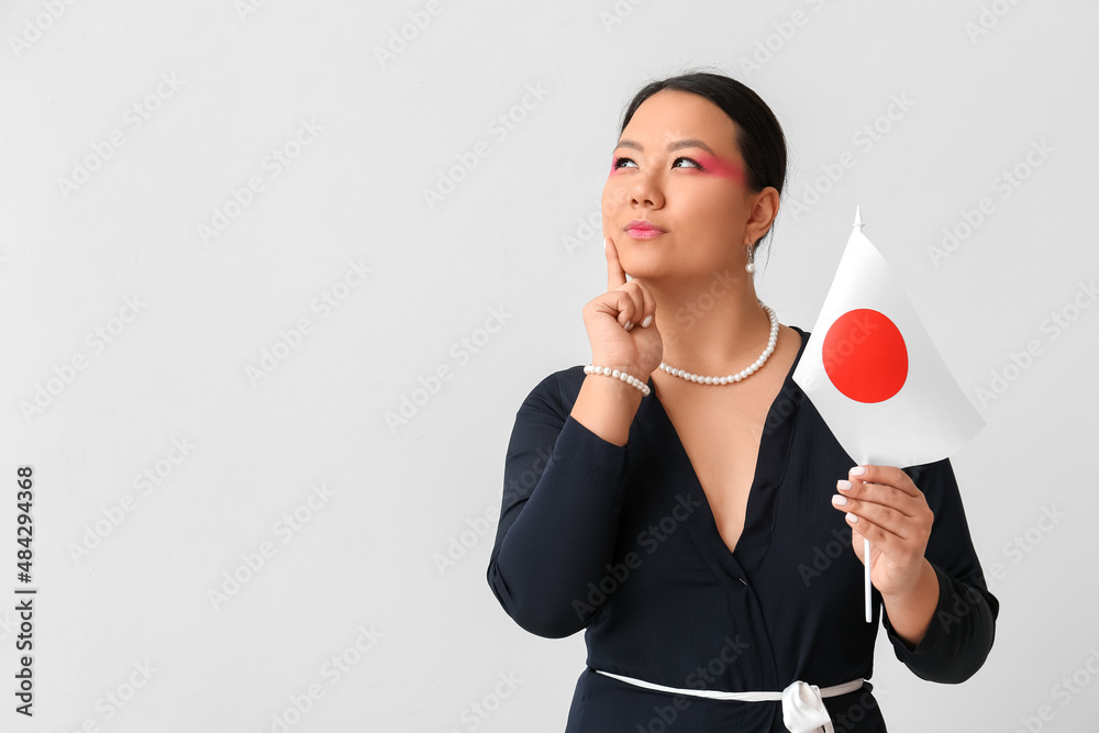 Beautiful young Asian woman with flag of Japan on light background Beautiful young Asian woman with flag of Japan on light background