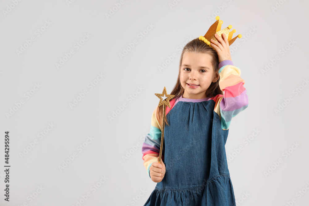 Cute girl in golden crown with magic wand on light grey background ...