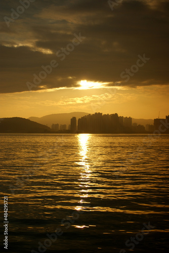 The silhouette of the sea and city reflecting the golden sunset.