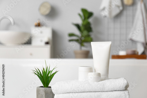 Set of cosmetic products, towels and plant in bathroom