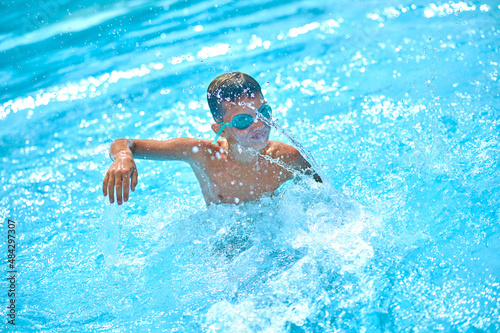 Boy in pool swimming raising his hand