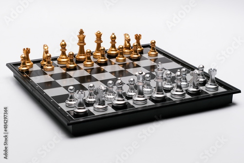 Golden and silver chess pieces arranged on a chessboard against a white background.