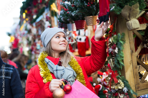 Young positive girl shopping decorations on traditional Christmas market in Spain