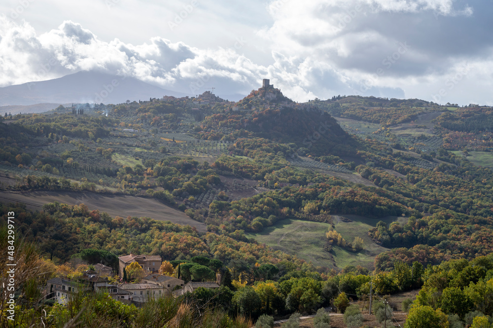 Naklejka premium Hiking on hills of Val d'Orcia near Bagno Vignoni, Tuscany, Italy. Tuscan landscape with cypress trees, vineyards, forests and ploughed fields in autumn.
