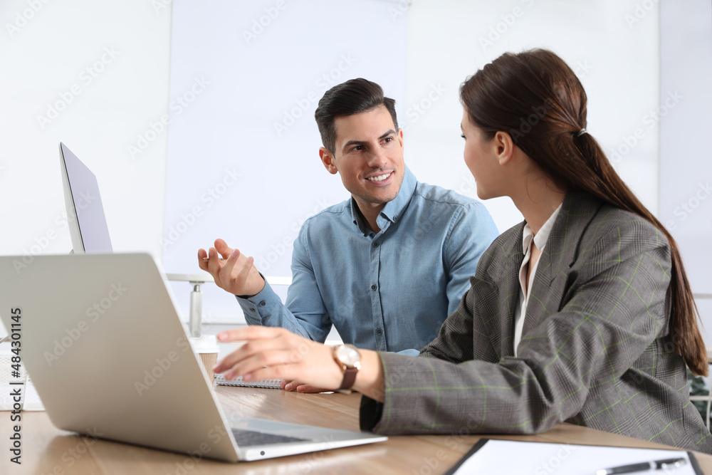 Businesswoman helping intern with work in office Businesswoman helping intern with work in office