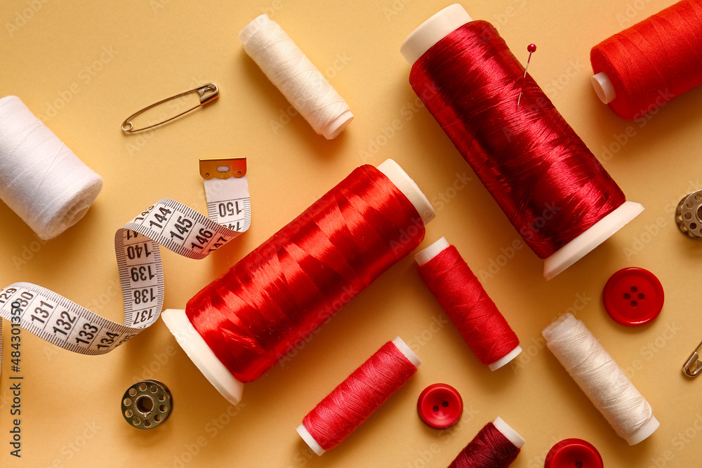 Thread spools, buttons and measuring tape on color background Thread spools, buttons and measuring tape on color background