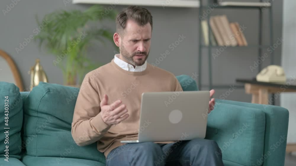 Man with Laptop Reacting to Loss on Sofa 