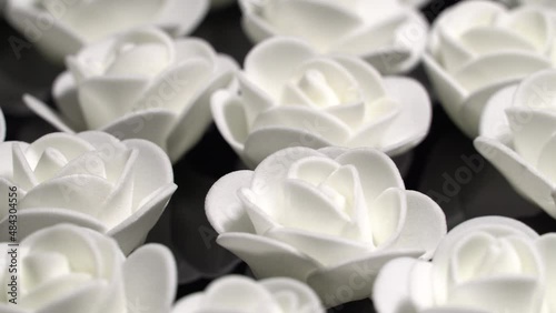 White decorative roses on a black plate, rotation  background. Close up
