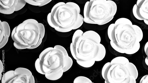 White decorative roses on a black plate, rotation  background. Close up