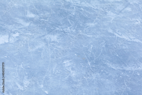 Empty ice rink with skate marks after the session outdoor. skating ice rink texture covered with snow in daylight. Close up of blue ice rink floor, copy space