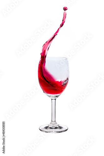 Red wine splash into glass on white background.