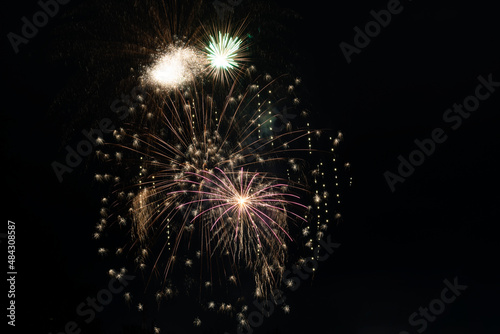 Bright fiery rays from exploding pyrotechnics against the black background of the night sky. Background with festive fireworks.