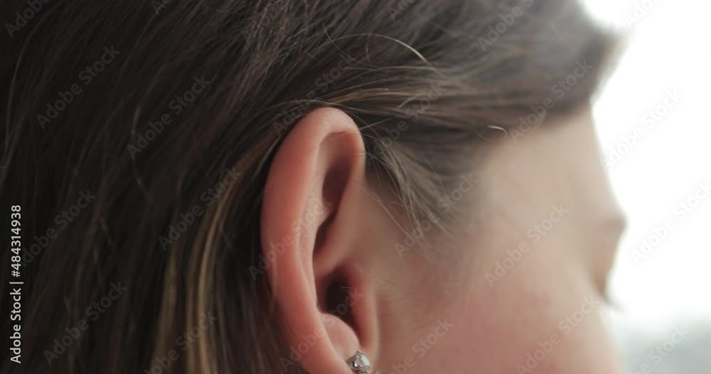 Girl with hearing problems uses a hearing aid after visiting an otolaryngologist. Technology helps people with disabilities in their daily lives. Young deaf woman adjusting hearing aid to environment. Girl with hearing problems uses a hearing aid after visiting an otolaryngologist. Technology helps people with disabilities in their daily lives. Young deaf woman adjusting hearing aid to environment.