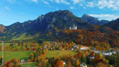 Relaxing view of drone lowering down towards village houses towards castle on hill over scenic autumn field in the afternoon near the Neuschwanstein Castle in Germany, Europe, wide view photo