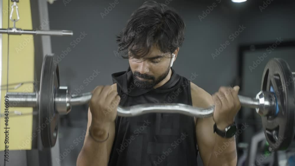 Young Indian bodybuilder busy doing biceps workout by lifting weight ...