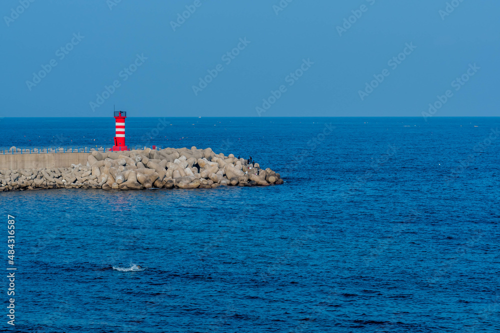 Red and white striped lighthouse on concrete pier Red and white striped lighthouse on concrete pier