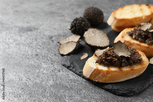 Delicious bruschettas with truffle sauce on grey table, closeup. Space for text