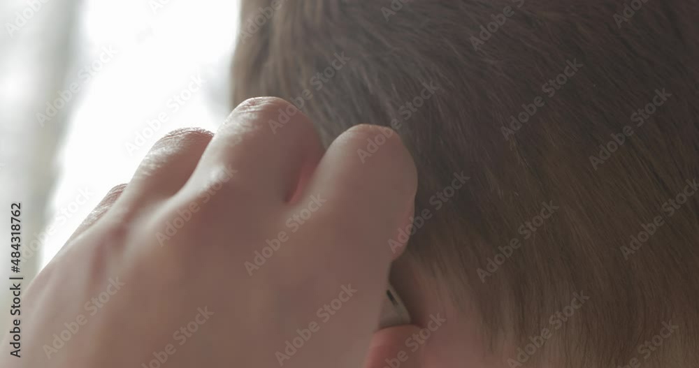 Boy with hearing problems uses a hearing aid after visiting an otolaryngologist. Technology helps people with disabilities in their daily lives. Young deaf man adjusting hearing aid to environment. Boy with hearing problems uses a hearing aid after visiting an otolaryngologist. Technology helps people with disabilities in their daily lives. Young deaf man adjusting hearing aid to environment.