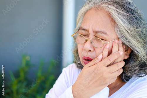 Asian elderly woman has toothache Put your hand over your mouth. The concept of oral health care of seniors. Diseases of the elderly. retirement health insurance