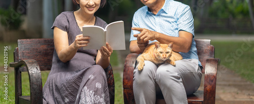 Photography Middle aged couple and cat are relax sitting on bench in backyard