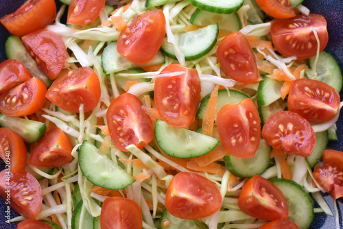 Vegetables salad with cucumber, carrot, tomato and cabbage on a plate.