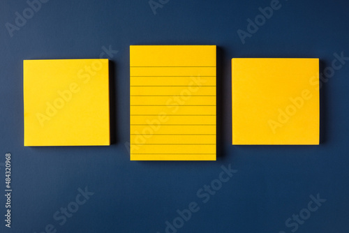 blank yellow sticky note on navy blue table background