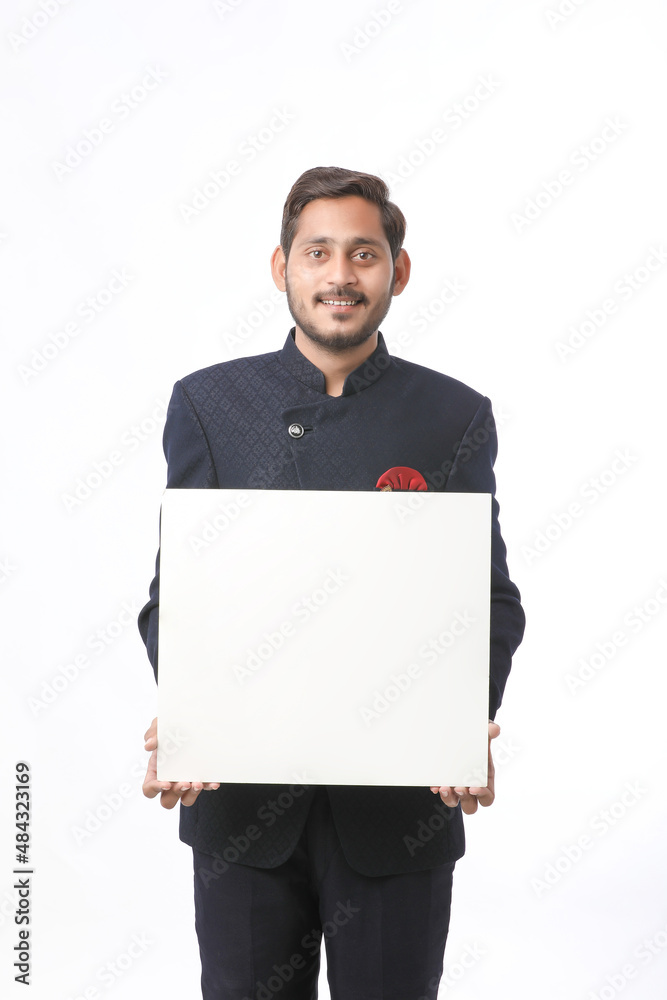 Indian man holding white board, promoting offers on festival season while wearing traditional cloths, standing over white background. Indian man holding white board, promoting offers on festival season while wearing traditional cloths, standing over white background.