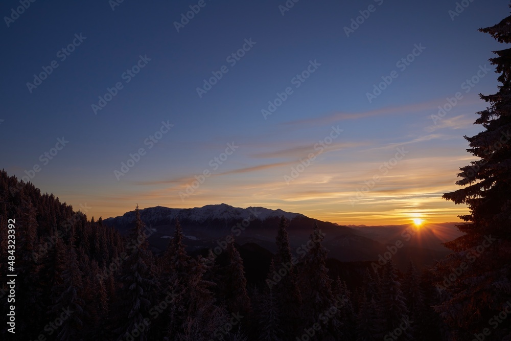 Alpine winter scenery with foggy valleys at the base of Piatra Craiului and Postavaru mountains at sunset Alpine winter scenery with foggy valleys at the base of Piatra Craiului and Postavaru mountains at sunset