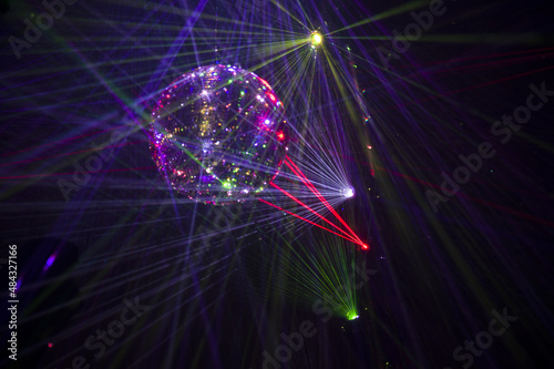 Mirrored Disco Ball and bright beams at the night party. Party attribute reflects Lazer lights. Abstract background with defocused rays. Night club atmosphere. Installation at Vilnius light festival