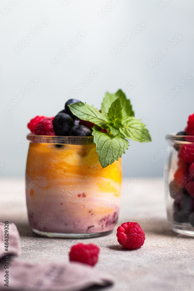 yogurt with mango and berry jam with blueberry, raspberry and mint leaves in the glass yogurt with mango and berry jam with blueberry, raspberry and mint leaves in the glass