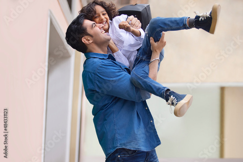 Father picking up and caressing his son wearing school uniform