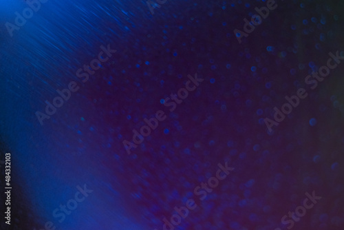 Blur light overlay. Bokeh glow. Underwater bubbles. Defocused neon purple blue color radiance grain texture on dark abstract background.