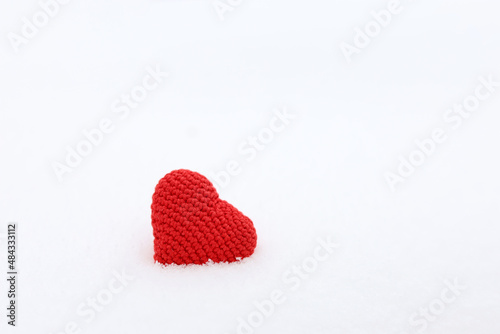 Red knitted heart in the snow. White background for Valentine s card  romantic love